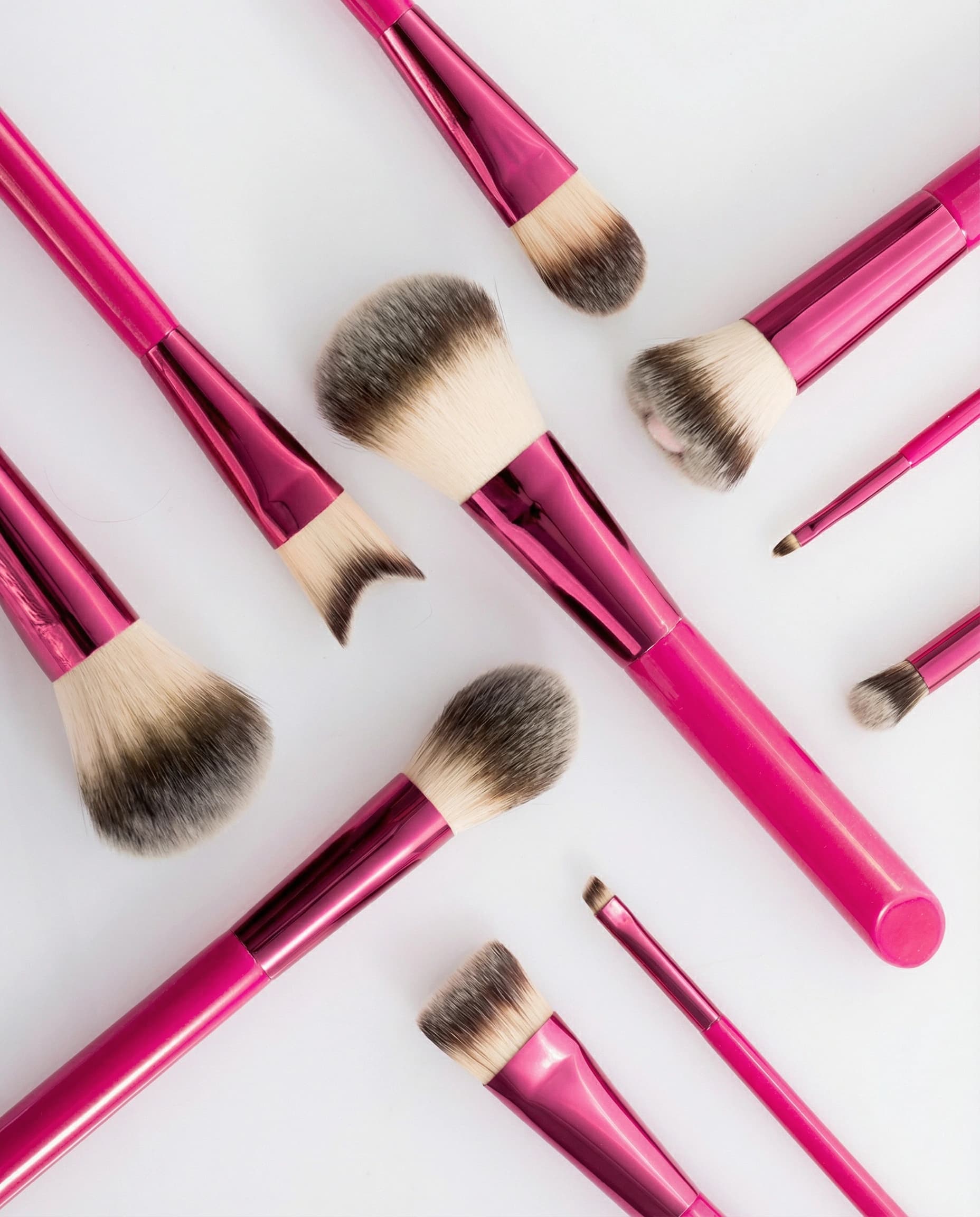 rose red cosmetic brushes with angled wooden handles in a flat lay